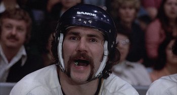Movie still from “Slap Shot” (1977), directed by George Roy Hill – A person wearing a hockey helmet; Close Up shot, Low angle