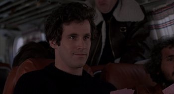 Movie still from “Slap Shot” (1977), directed by George Roy Hill – A young man sitting in a chair looking at the camera; Close Up shot, Over the shoulder angle