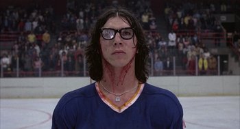 Movie still from “Slap Shot” (1977), directed by George Roy Hill – A man with blood all over his face and neck; Medium shot, Low angle