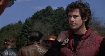 Movie still from “Slap Shot” (1977), directed by George Roy Hill – A man in a red jacket is putting on his jacket; Close Up shot, Over the shoulder angle