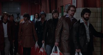 Movie still from “Slap Shot” (1977), directed by George Roy Hill – A group of people standing next to each other holding shopping bags; Medium shot, High angle