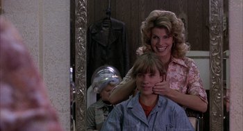 Movie still from “Slap Shot” (1977), directed by George Roy Hill – A woman and a boy getting their hair cut in front of a mirror; Medium shot, Over the shoulder angle