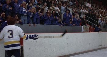 Movie still from “Slap Shot” (1977), directed by George Roy Hill – A crowd watches as a hockey player falls in front of a crowd; Wide shot, High angle