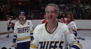 Movie still from “Slap Shot” (1977), directed by George Roy Hill – A hockey player with blood all over his face; Medium shot, Low angle