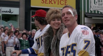 Movie still from “Slap Shot” (1977), directed by George Roy Hill – A man and a woman wearing hockey uniforms; Medium shot, Low angle