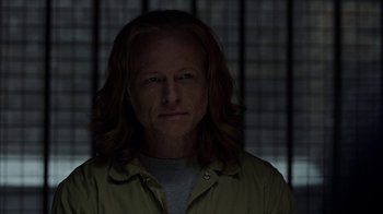 Movie still from “Slasher” (2016), created by Aaron Martin – A man with long hair is in a dark room; Close Up shot, Over the shoulder angle