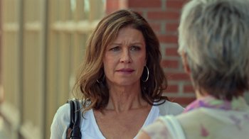 Movie still from “Slasher” (2016), created by Aaron Martin – A person with a purse near a brick wall; Close Up shot, Over the shoulder angle