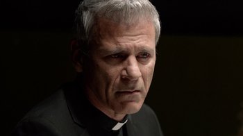 Movie still from “Slasher” (2016), created by Aaron Martin – An older man wearing a priest's collar; Close Up shot, Over the shoulder angle