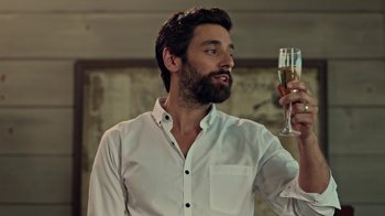 Movie still from “Slasher” (2016), created by Aaron Martin – A man holding a glass of wine in his hand; Close Up shot, Over the shoulder angle