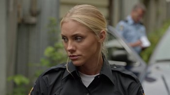 Movie still from “Slasher” (2016), created by Aaron Martin – A woman with blonde hair wearing a police uniform; Close Up shot, Over the shoulder angle
