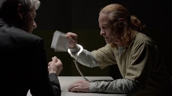 Movie still from “Slasher” (2016), created by Aaron Martin – A man in a jail cell holding a handcuff; Medium shot, Over the shoulder angle