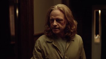 Movie still from “Slasher” (2016), created by Aaron Martin – A man with long blonde hair wearing a tan jacket; Close Up shot, Over the shoulder angle