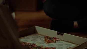 Movie still from “Slasher” (2016), created by Aaron Martin – A pizza sitting in a pizza box on top of a table; Extreme Close Up shot, High angle