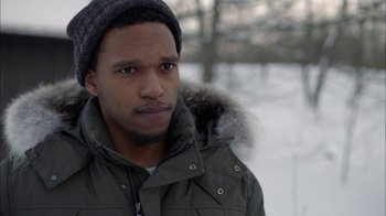 Movie still from “Slasher” (2016), created by Aaron Martin – A man in a winter coat and a hat is standing in the snow; Close Up shot, Over the shoulder angle