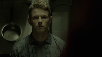 Movie still from “Slasher” (2016), created by Aaron Martin – A man in a green shirt is looking at the camera; Close Up shot, Low angle