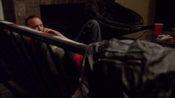 Movie still from “Breaking Bad” (2008), created by Vince Gilligan – A man sitting on a couch next to a chair; Medium shot, High angle