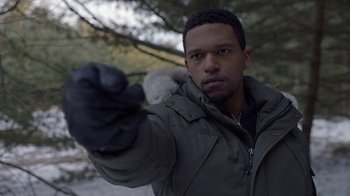 Movie still from “Slasher” (2016), created by Aaron Martin – A man in winter clothes and gloves pointing at the camera; Close Up shot, Over the shoulder angle