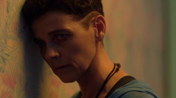 Movie still from “Slasher” (2016), created by Aaron Martin – A person wearing a necklace; Close Up shot, Over the shoulder angle