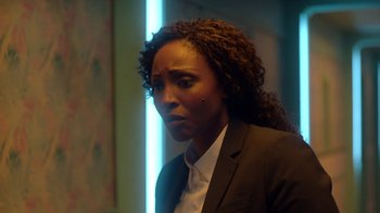 Movie still from “Slasher” (2016), created by Aaron Martin – A woman in a black suit and a white shirt; Close Up shot, Over the shoulder angle