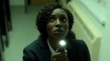 Movie still from “Slasher” (2016), created by Aaron Martin – A woman is holding a flashlight up to her face; Close Up shot, High angle