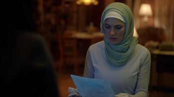 Movie still from “Slasher” (2016), created by Aaron Martin – A woman wearing a green headscarf looking at a paper; Close Up shot, Over the shoulder angle
