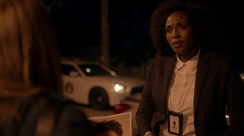 Movie still from “Slasher” (2016), created by Aaron Martin – A woman in a suit is standing in front of a white car; Close Up shot, Over the shoulder angle