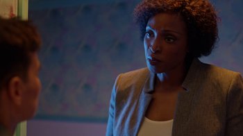 Movie still from “Slasher” (2016), created by Aaron Martin – A woman in a gray jacket is looking at the camera; Close Up shot, Over the shoulder angle