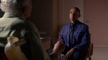 Movie still from “Breaking Bad” (2008), created by Vince Gilligan – A man in a suit and tie talking to another man in a suit; Medium shot, Over the shoulder angle
