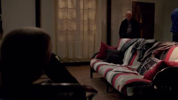 Movie still from “Breaking Bad” (2008), created by Vince Gilligan – A man sitting on top of a couch in a living room; Wide shot, Over the shoulder angle
