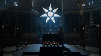 Movie still from “Game of Thrones” (2011), created by D.B. Weiss – A man sitting in front of a star on a stage; Extreme Wide shot, Low angle