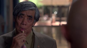 Movie still from “Breaking Bad” (2008), created by Vince Gilligan – An older man in a suit and tie is smoking a cigarette; Close Up shot, Over the shoulder angle