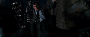 Movie still from “Spider-Man 3” (2007), directed by Sam Raimi – A man wearing a suit and tie leaning against a wall; Wide shot, High angle