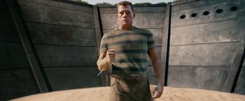 Movie still from “Spider-Man 3” (2007), directed by Sam Raimi – A man standing in the sand holding a knife; Medium shot, Low angle