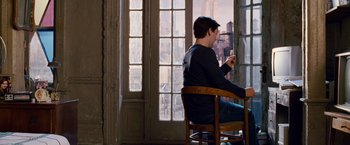 Movie still from “Spider-Man 3” (2007), directed by Sam Raimi – A man sitting in a chair in front of a window; Wide shot, Over the shoulder angle
