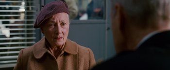 Movie still from “Spider-Man 3” (2007), directed by Sam Raimi – An older woman wearing a brown coat and a purple hat; Close Up shot, Over the shoulder angle