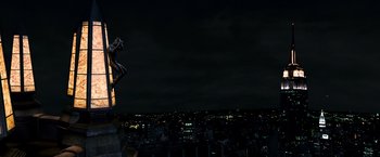Movie still from “Spider-Man 3” (2007), directed by Sam Raimi – A night time view of a city with a statue on top of it; Extreme Wide shot, High angle