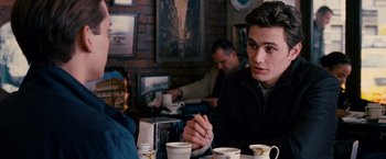 Movie still from “Spider-Man 3” (2007), directed by Sam Raimi – A man sitting at a table with two cups of coffee in front of him; Medium shot, Over the shoulder angle
