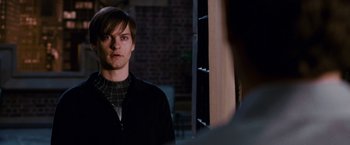 Movie still from “Spider-Man 3” (2007), directed by Sam Raimi – A man in a black jacket standing in front of a brick wall; Close Up shot, Over the shoulder angle
