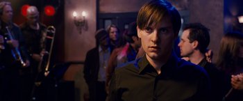 Movie still from “Spider-Man 3” (2007), directed by Sam Raimi – A man in black shirt standing in front of a group of people; Close Up shot, Over the shoulder angle