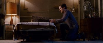 Movie still from “Spider-Man 3” (2007), directed by Sam Raimi – A man kneeling down in front of a bed; Wide shot, High angle