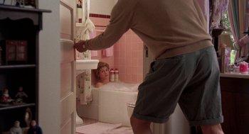 Movie still from “Steel Magnolias” (1989), directed by Herbert Ross – A man in a bathroom taking a picture of a woman in a bathtub; Medium shot, Over the shoulder angle