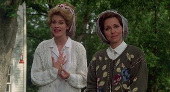 Movie still from “Steel Magnolias” (1989), directed by Herbert Ross – Two women standing next to each other in front of a forest; Medium shot, Low angle