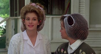 Movie still from “Steel Magnolias” (1989), directed by Herbert Ross – Two women with long hair and a veil on their head; Close Up shot, Over the shoulder angle