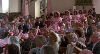 Movie still from “Steel Magnolias” (1989), directed by Herbert Ross – A group of people sitting in a room with pink dresses on them; Wide shot, High angle