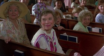 Movie still from “Steel Magnolias” (1989), directed by Herbert Ross – An older woman sitting in a church with other people in the background; Close Up shot, Over the shoulder angle