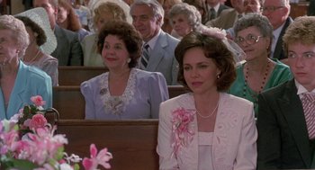 Movie still from “Steel Magnolias” (1989), directed by Herbert Ross – A woman sitting in front of other people in a church; Medium shot, Over the shoulder angle