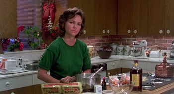 Movie still from “Steel Magnolias” (1989), directed by Herbert Ross – A woman sitting at a kitchen table in front of a pot; Medium shot, Over the shoulder angle