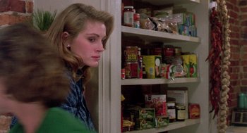 Movie still from “Steel Magnolias” (1989), directed by Herbert Ross – A woman standing next to a shelf filled with food; Close Up shot, Over the shoulder angle