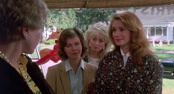 Movie still from “Steel Magnolias” (1989), directed by Herbert Ross – A group of women standing next to each other in front of trees; Medium shot, Over the shoulder angle