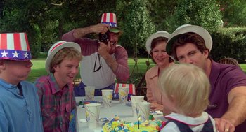 Movie still from “Steel Magnolias” (1989), directed by Herbert Ross – A man taking a picture of a group of people sitting at a table; Medium shot, Over the shoulder angle